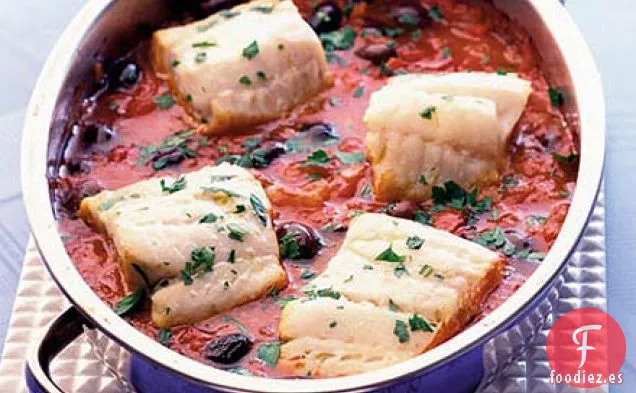 Pescado de una olla con aceitunas negras y tomates